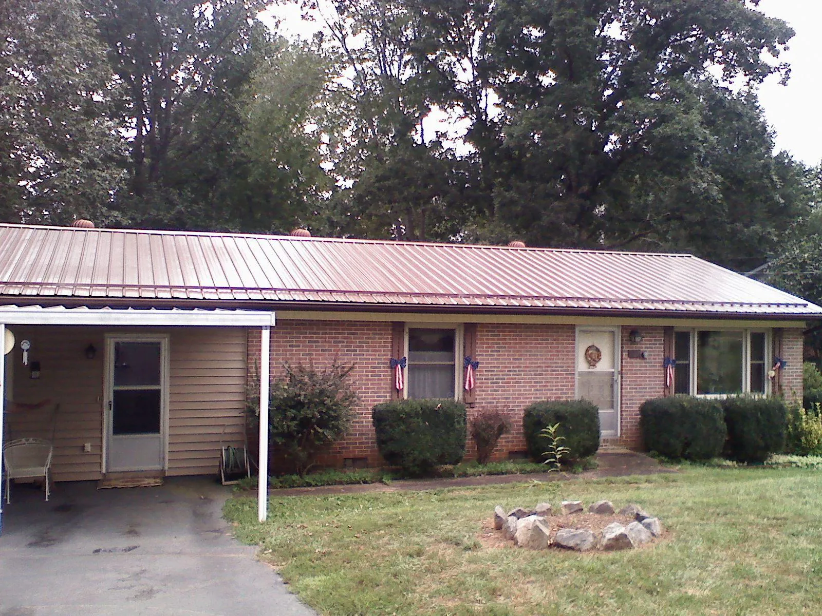 Bronze metal roof and carport on a brick ranch home — Roof Repair work by our crew in Willard